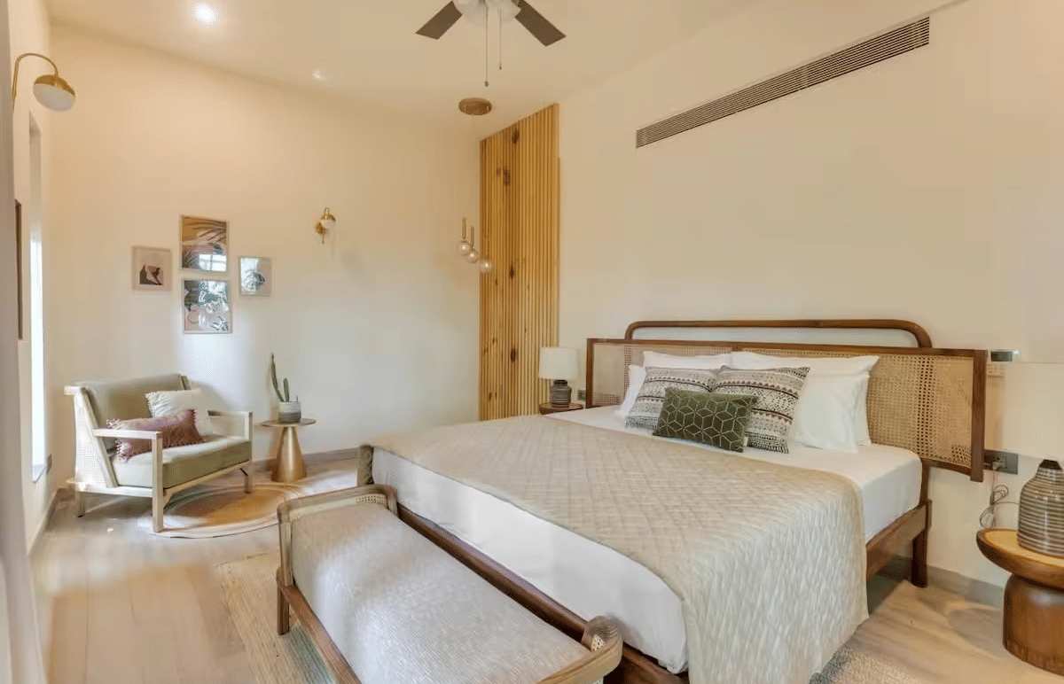 Spacious room with a neatly made bed, bedside table, seating at the foot of the bed, and a cushioned sofa at Lime Tree Villa with Private Pool | Luxury Stay in Goa.